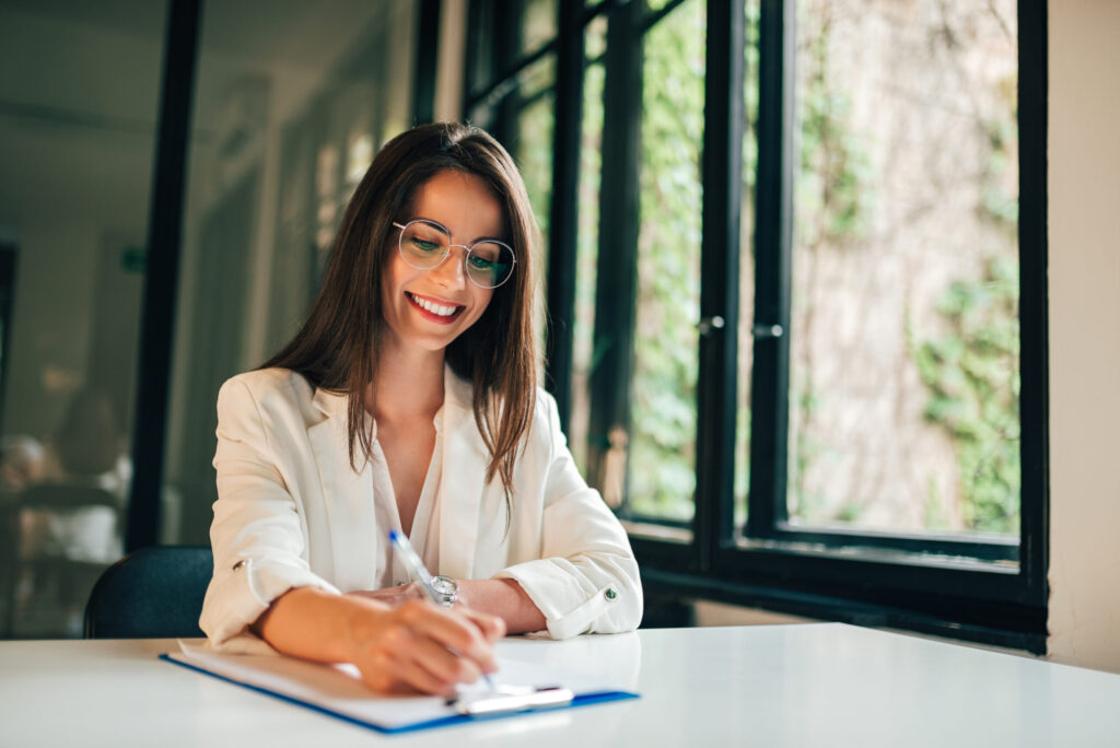 Smiling elegant businesswoman or student filling application form.